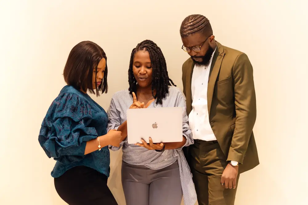 Three colleagues looking at the same laptop screen